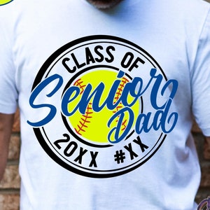 May include: White t-shirt with a black and white circle graphic. The graphic features a softball, the text "Class of Senior Dad 20XX #XX", and blue text that says "Senior".