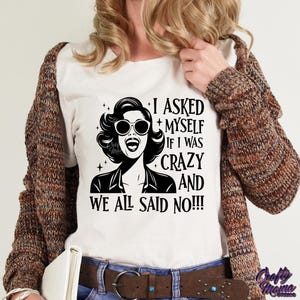 May include: A white t-shirt with a black and white illustration of a woman with sunglasses and the text "I asked myself if I was crazy and we all said no!!!"