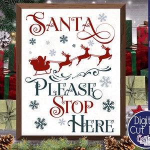 May include: A white sign with a red wooden frame features a red and white Santa Claus design with the text "Santa Please Stop Here".