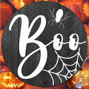 K&ouml;nnte beinhalten: Ein schwarz-wei&szlig;es Halloween-Schild mit dem Wort "Boo" in einer verspielten Schrift. Hinter dem Wort "Boo" befindet sich eine Spinne mit einem Netz.