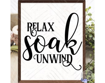 Może przedstawiać: Oprawiony drewniany znak z czarnym napisem "RELAX SOAK UNWIND". Tło jest białe z subtelnym, teksturowanym wzorem. Znak otoczony jest zielenią.