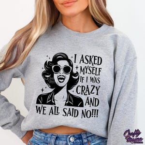 May include: Gray sweatshirt with a black and white graphic of a woman with sunglasses and the text "I asked myself if I was crazy and we all said no!!!"