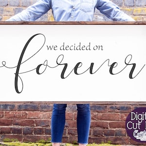 May include: A white wooden sign with the text "we decided on forever" in black cursive font. The sign is being held by a person.