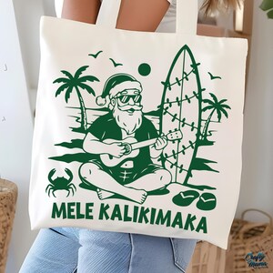 May include: Off-white tote bag with a green graphic of Santa Claus playing a ukulele on a beach, with a surfboard, palm trees, and the text "MELE KALIKIMAKA". The design is a festive holiday theme.