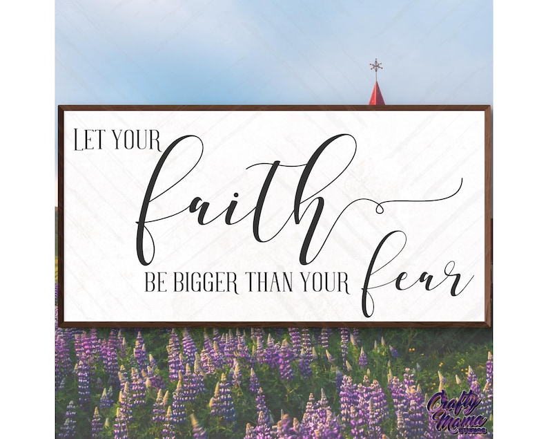 May include: A white wooden sign with black text that reads "Let your faith be bigger than your fear". The sign is in front of a field of purple flowers.