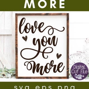 May include: A white sign with a brown wooden frame, featuring the text "love you more" in a cursive font with two small hearts on either side of the word "you". The sign is displayed on a white wooden surface with green foliage in the background. The text "svg eps png dxf jpg" is displayed below the sign.