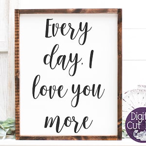 May include: A white sign with a brown wood frame, featuring the text "Every day. I love you more" in black cursive font.