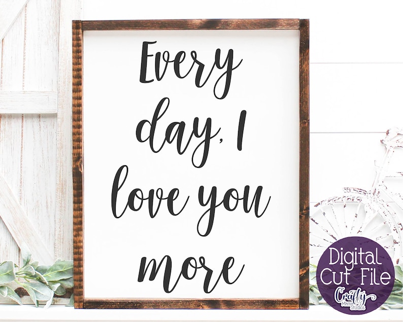 May include: A white sign with a brown wood frame, featuring the text "Every day. I love you more" in black cursive font.