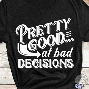 May include: Dark gray t-shirt with the white text "PRETTY GOOD... at bad DECISIONS". The text is in a bold, stylized font. The shirt has short sleeves and a crew neck.