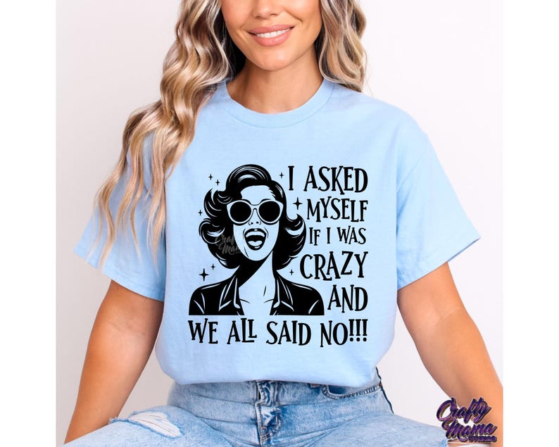 May include: A light blue t-shirt with a black and white graphic of a woman wearing sunglasses and the text "I asked myself if I was crazy and we all said no!!!"