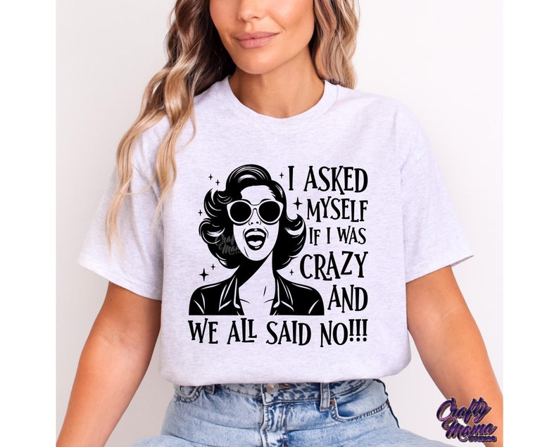 May include: A white t-shirt with a black and white graphic design featuring a woman with sunglasses and the text "I asked myself if I was crazy and we all said no!!!"