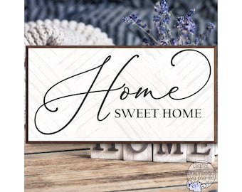 May include: A rectangular wooden sign with the words "Home Sweet Home" in elegant black script. The sign has a white background with a subtle wood grain pattern and a dark brown frame. The sign is a decorative item.