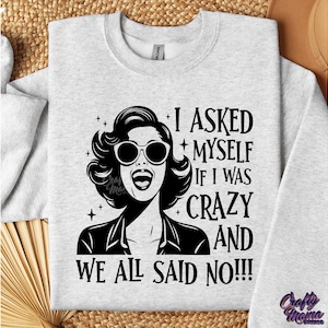 May include: A gray sweatshirt with a black and white graphic design featuring a woman with a quote that reads "I asked myself if I was crazy and we all said no!!!"