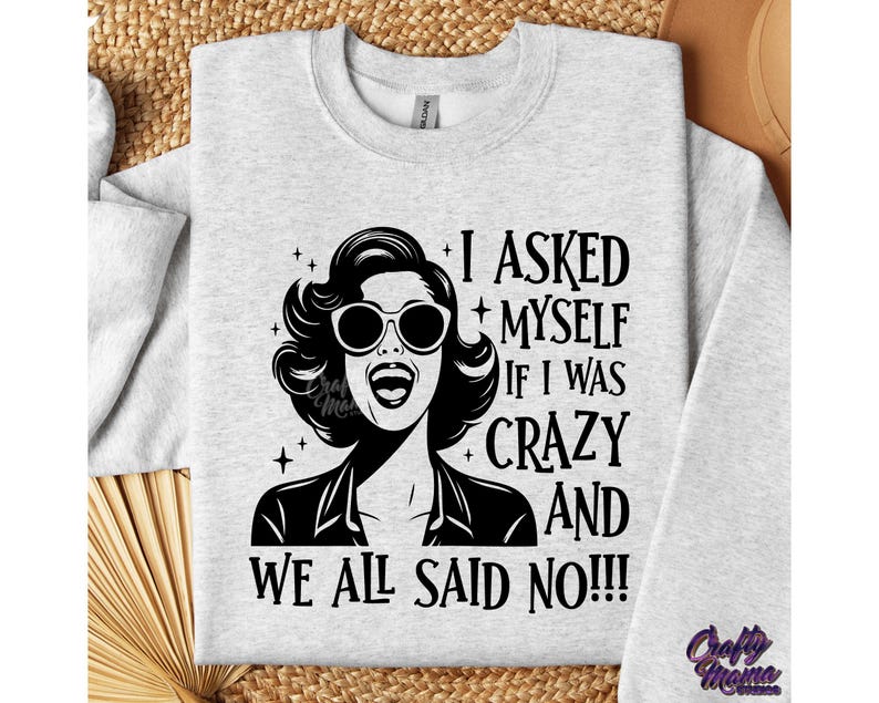 May include: A gray sweatshirt with a black and white graphic design featuring a woman with a quote that reads "I asked myself if I was crazy and we all said no!!!"