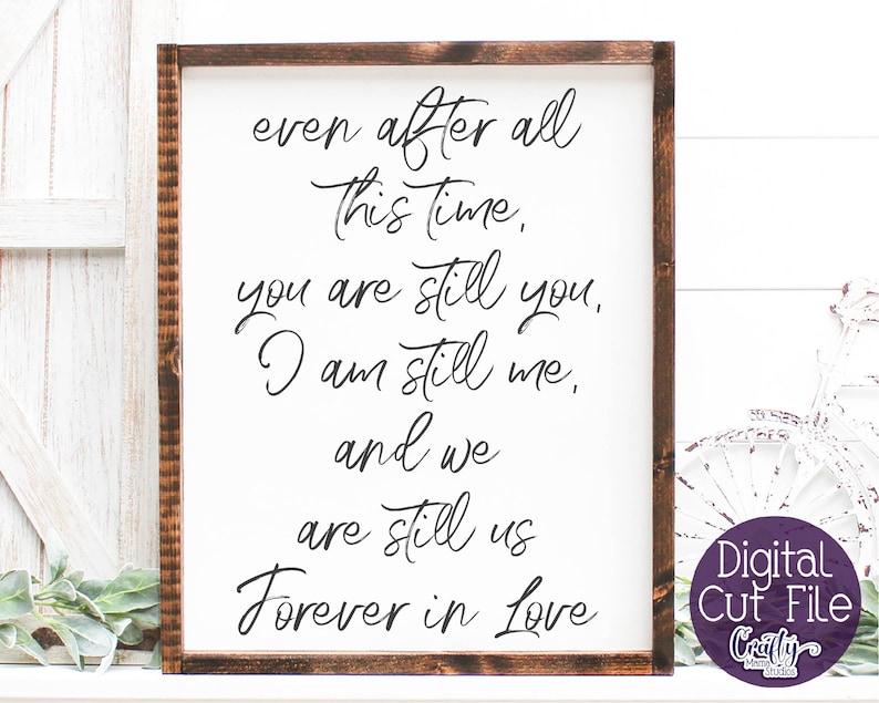 May include: A white sign with a brown wooden frame, featuring a handwritten message that reads "even after all this time, you are still you, I am still me, and we are still us forever in love".