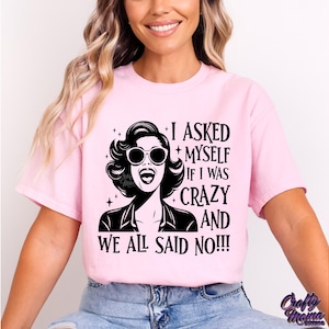 May include: Pink t-shirt with a black and white graphic of a woman wearing sunglasses and the text "I asked myself if I was crazy and we all said no!!"