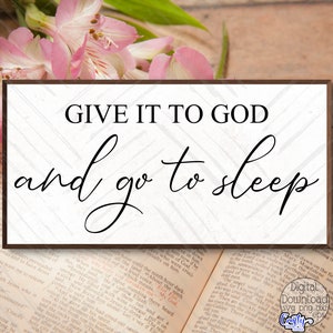 May include: A white sign with a brown frame and a black chevron pattern background. The sign reads "GIVE IT TO GOD and go to sleep".