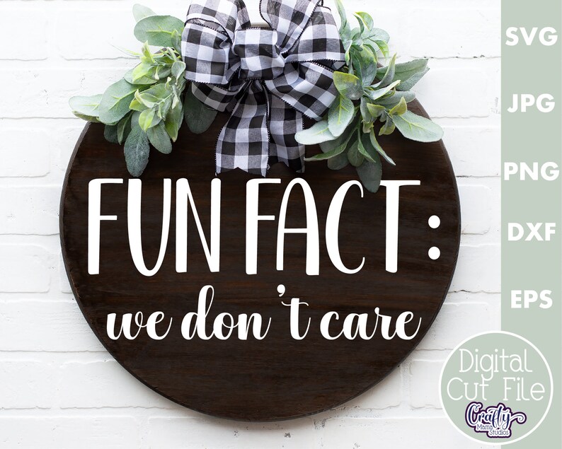 K&ouml;nnte beinhalten: Ein rundes Holzschild mit einer schwarz-wei&szlig;en karierten Schleife und Gr&uuml;n. Das Schild sagt "FUN FACT: we don't care".