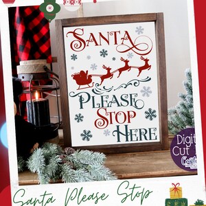 May include: A white sign with a brown wooden frame, featuring a red and white illustration of Santa Claus in a sleigh pulled by reindeer. The text "SANTA PLEASE STOP HERE" is written in red and blue cursive lettering with snowflakes scattered around the text.