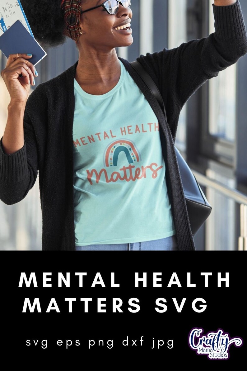 May include: A light blue t-shirt with the text "Mental Health Matters" and a rainbow graphic. The text is in a white font. The rainbow is made up of different colors, including red, orange, yellow, green, blue, indigo, and violet. The shirt is being worn by a person with a black cardigan and a black bag.