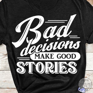 May include: Dark gray t-shirt with the white text "Bad decisions make good stories." The text is in a bold, stylized font. The shirt has short sleeves and a crew neck.