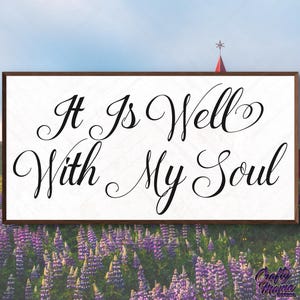 May include: A wooden sign with the text "It Is Well With My Soul" in a decorative script font. The sign is framed in brown and has a white background. The sign is displayed in front of a field of purple lupine flowers.
