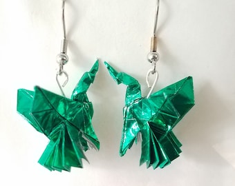 Può includere: Un paio di orecchini a forma di uccello origami verde con ganci d'argento. Gli uccelli sono fatti di carta piegata con un bagliore metallico.