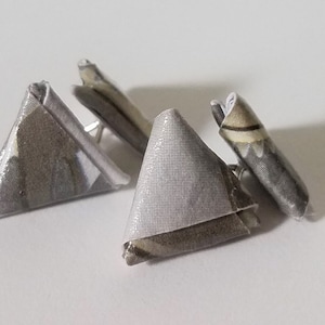 May include: A pair of triangular earrings made from fabric with a grey and white pattern.