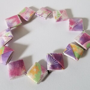 May include: A circle of origami paper squares in shades of pink, purple, and green with floral patterns.