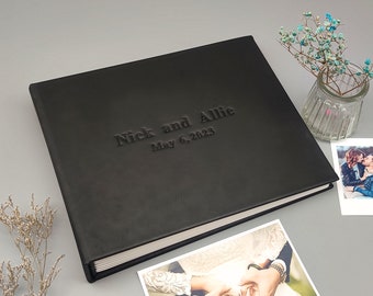 May include: Black leather photo album with the text "Nick and Allie May 6, 2023" embossed on the front cover.