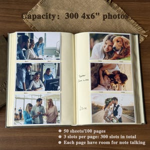 Peut inclure: Album photo ouvert avec six emplacements pour photos de 10x15 cm, chacun contenant une photographie. L'album est ouvert sur une double page avec des photos de personnes. Le texte sur l'album indique "Capacity: 300 4x6" photos". L'album contient 50 feuilles/100 pages.