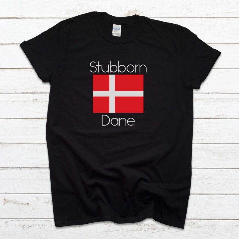 May include: Black t-shirt with white text that reads "Stubborn Dane" and a red and white Danish flag.