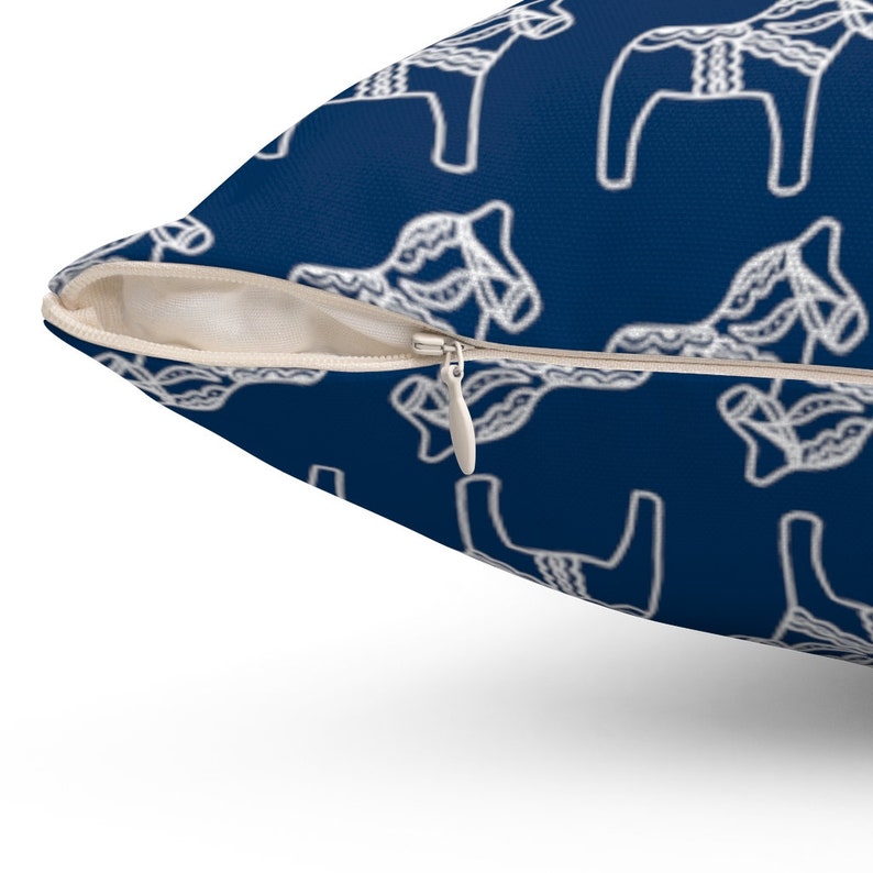 Puede incluir: Una almohada azul marino con un patr&oacute;n de caballo Dala escandinavo blanco. La almohada tiene una cremallera.