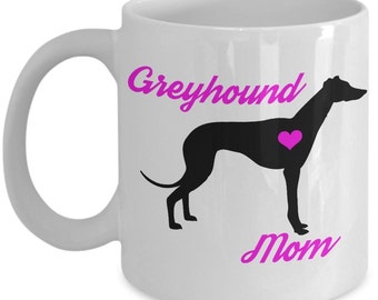 May include: White ceramic coffee mug with a black silhouette of a Greyhound dog with a pink heart on its chest. The text "Greyhound Mom" is written in pink cursive.