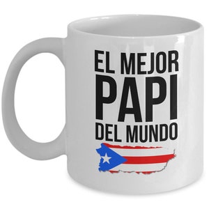 May include: White ceramic coffee mug with a black and white graphic that says "El Mejor Papi Del Mundo" with a red, white and blue Puerto Rican flag graphic.