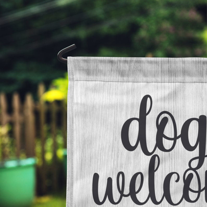 May include: White garden flag with black text that reads "dogs welcome".