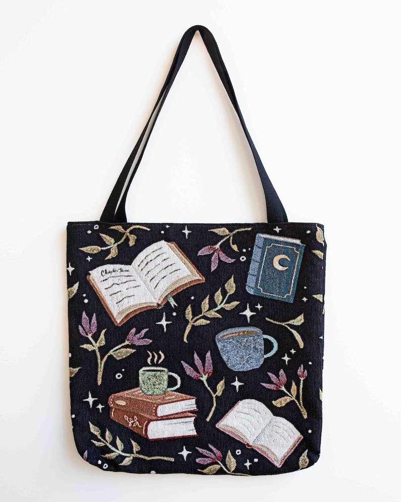 May include: Black tote bag with a whimsical design featuring books, coffee cups, and stars. The text "Chapter One" is visible on one of the books.