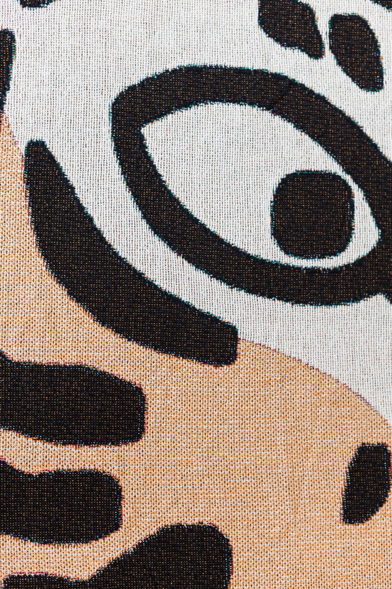 May include: Close-up of a woven fabric with a black and white geometric pattern. The fabric has a textured surface and a subtle sheen.