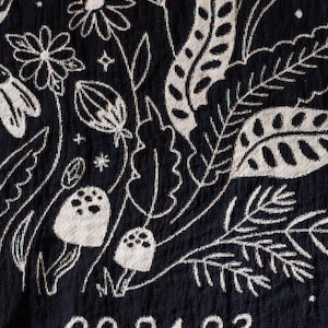 May include: Black fabric with a white floral design and the date 09.24.23 embroidered in white.