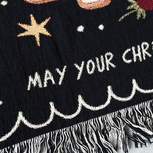 K&ouml;nnte beinhalten: Schwarze gewebte Wurfdecke mit wei&szlig;em Fransenrand. Die Decke zeigt ein farbenfrohes Design mit einem Stern, einer Palme und dem Text "MAY YOUR CHRISTMAS".