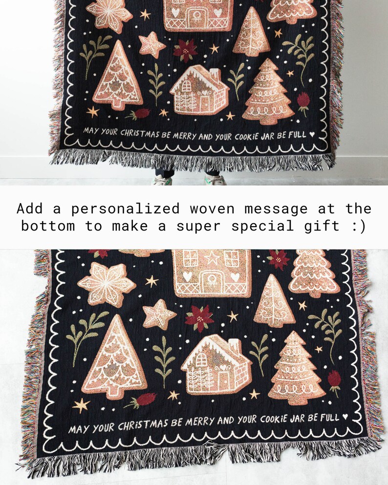 K&ouml;nnte beinhalten: Schwarze gewebte Wurfdecke mit Weihnachtsmotiv mit Lebkuchenh&auml;usern, Sternen und B&auml;umen. Die Decke hat einen Fransenrand und der Text "May your Christmas be merry and your cookie jar be full" ist in den unteren Rand eingewebt.