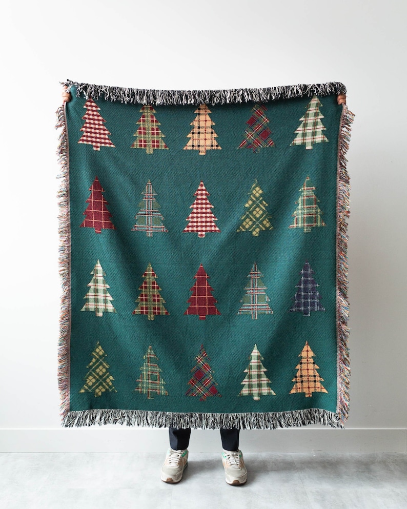 Op de afbeelding: Een turquoise geweven deken met een franje rand heeft een herhalend patroon van kleurrijke geruite kerstboom.