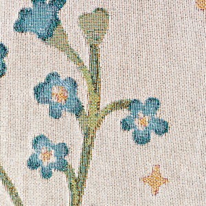 May include: Close-up of a woven fabric with a floral pattern. The design features blue flowers with yellow centers and green stems against a cream-colored background. Small gold star-shaped accents are also present.