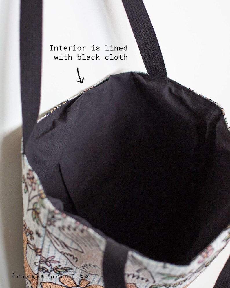 May include: A tote bag with a floral print and black straps. The interior is lined with black cloth.