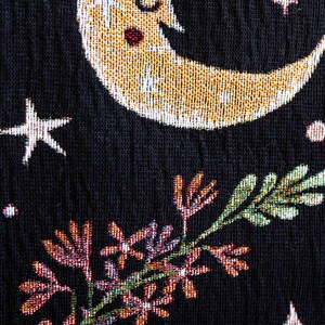 May include: A black fabric with a gold and white crescent moon with a sleeping face, green and pink floral designs, and white and gold stars.