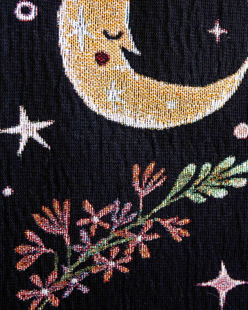 May include: A black fabric with a gold and white crescent moon with a sleeping face, green and pink floral designs, and white and gold stars.