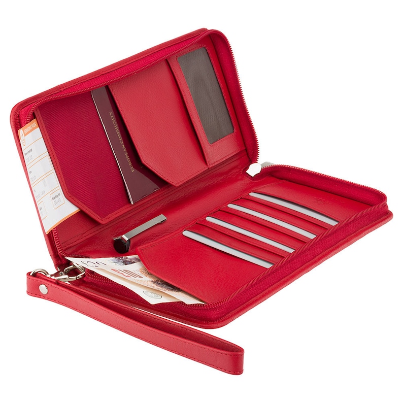 May include: Open red leather travel wallet with multiple compartments. Features include a passport slot, card slots, a pen holder, and a wrist strap. The wallet is zippered and contains currency.