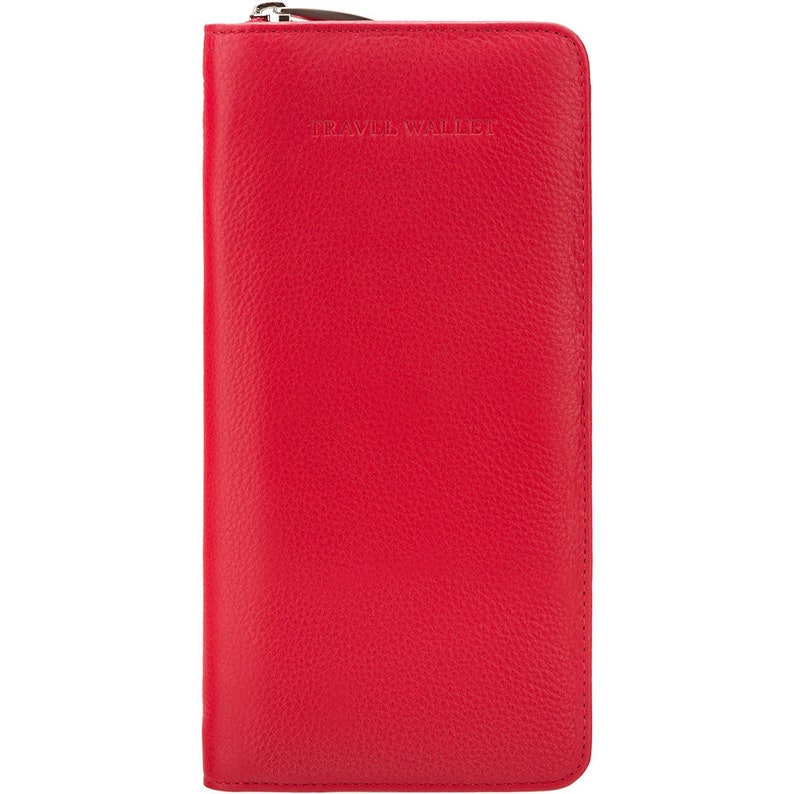 May include: A bright red travel wallet with a zipper closure. The wallet is rectangular and features the embossed text "TRAVEL WALLET" near the top. The material has a textured, leather-like appearance.