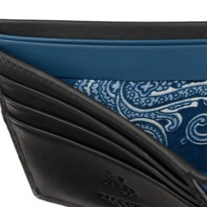 Puede incluir: Cartera de cuero negro con forro estampado de paisley. La cartera tiene m&uacute;ltiples ranuras para tarjetas y un portafolios.