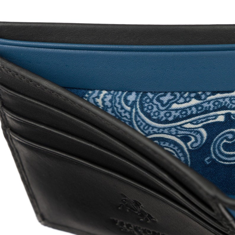 Puede incluir: Cartera de cuero negro con forro estampado de paisley. La cartera tiene m&uacute;ltiples ranuras para tarjetas y un portafolios.